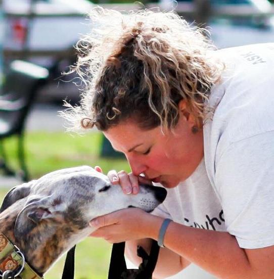a woman kissing a greyhound